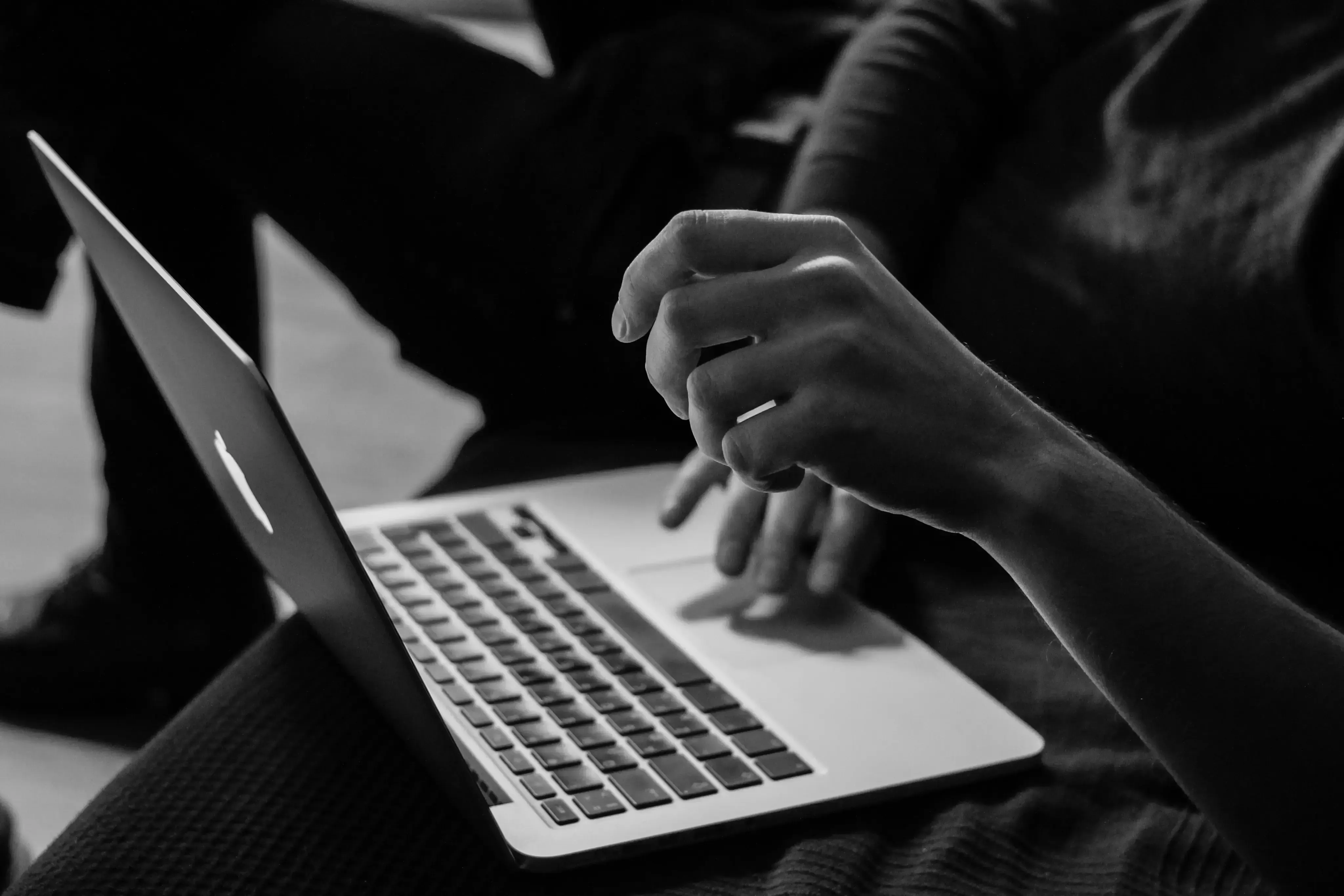 Person arbeitet konzentriert an einem aufgeklappten Laptop auf dem Schoß. | MH Consulting